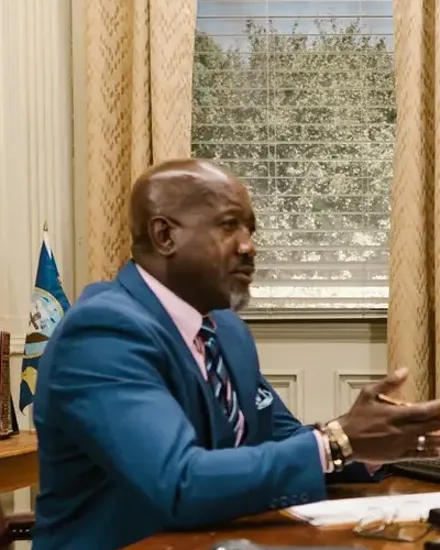 Sample portrait: a man in a blue suit speaking at a desk