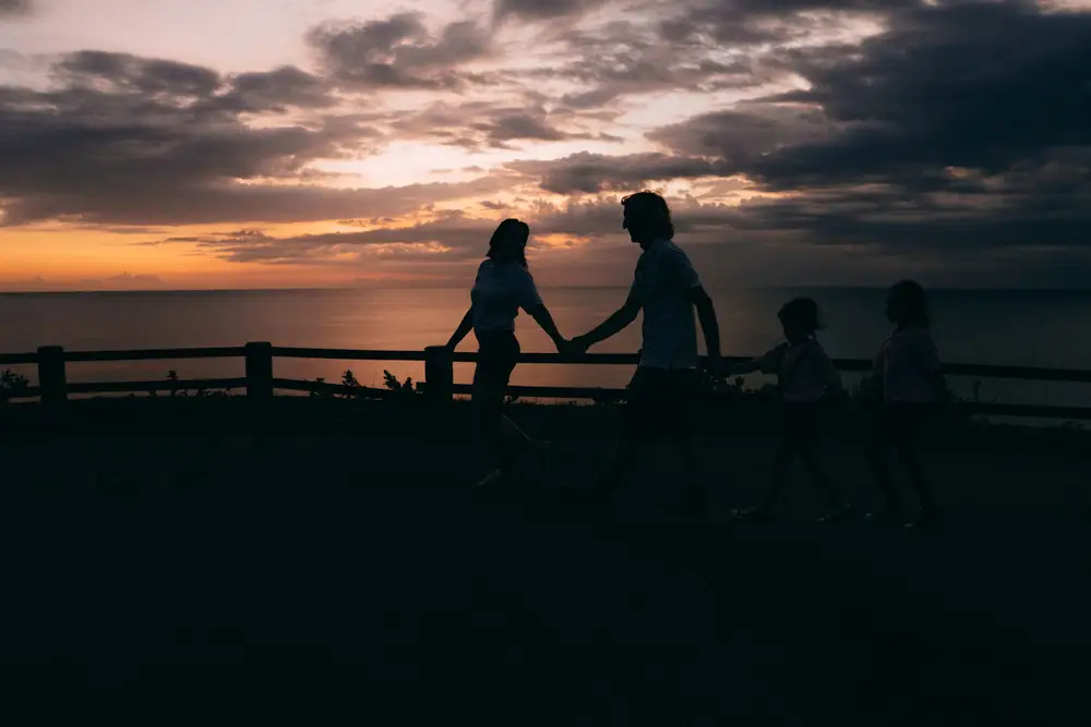 Silhouette of a family walking together at dusk by the sea